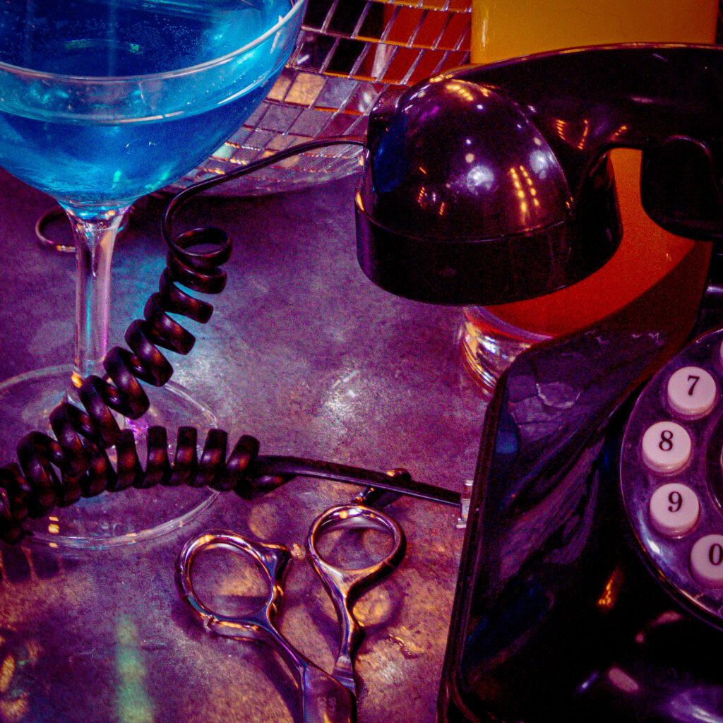 salon setting at shallows in manchester, a pair of scissors, a phone and a cocktail