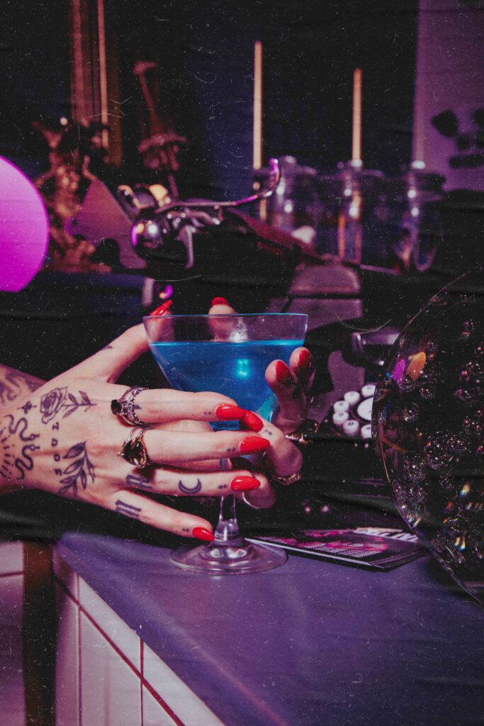 tattooed hands holding a mocktail at a speakeasy style bar